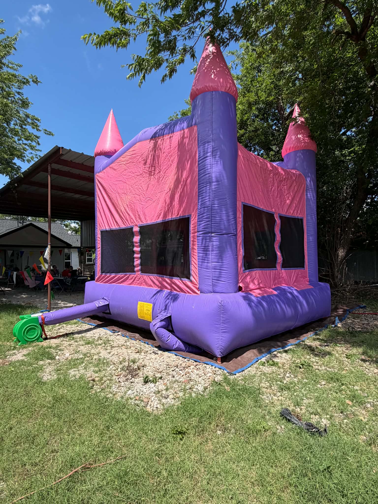 Sam Bros Party Rentals bounce house castle set up on green grass under a blue Texas sky